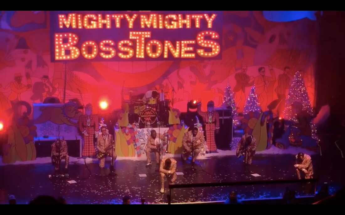 The Mighty Mighty Bosstones on a colorful winter-cartoony and holiday themed stage set all taking a knee